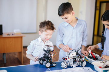 Little happy constructors kids playing with electrical robot while visiting robotics exhibition...