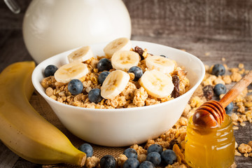 Healthy breakfast concept with oat flakes and fresh berries on rustic background. Food made of granola and muesli. Healthy banana smoothie with blackberries, honey and milk.