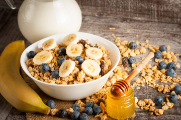 Healthy breakfast concept with oat flakes and fresh berries on rustic background. Food made of granola and muesli. Healthy banana smoothie with blackberries, honey and milk.