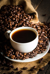 Coffee cup and beans on a rustic background. Coffee Espresso and a piece of cake with a curl. Cup of Coffee and coffee beans on table.
