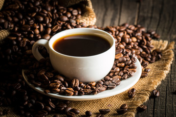 Coffee cup and beans on a rustic background. Coffee Espresso and a piece of cake with a curl. Cup of Coffee and coffee beans on table.