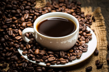 Coffee cup and beans on a rustic background. Coffee Espresso and a piece of cake with a curl. Cup of Coffee and coffee beans on table.