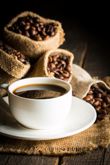 Coffee cup and beans on a rustic background. Coffee Espresso and a piece of cake with a curl. Cup of Coffee and coffee beans on table.