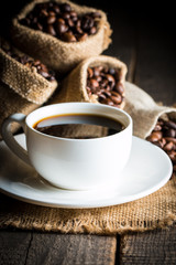 Coffee cup and beans on a rustic background. Coffee Espresso and a piece of cake with a curl. Cup of Coffee and coffee beans on table.