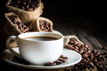 Coffee cup and beans on a rustic background. Coffee Espresso and a piece of cake with a curl. Cup of Coffee and coffee beans on table.