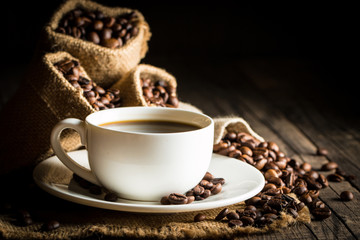 Coffee cup and beans on a rustic background. Coffee Espresso and a piece of cake with a curl. Cup of Coffee and coffee beans on table.