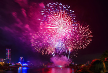 people look at the fireworks over the city pond and skyscrapers of the city center