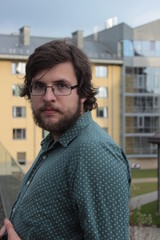 Portrait of a young man with a beard in glasses at the background of the office