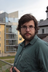 Portrait of a young man with a beard in glasses at the background of the office