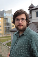 Fototapeta premium Portrait of a young man with a beard in glasses at the background of the office