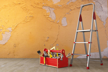 Home renovation and improvement concept. Ladder, toolbox with tools and old grunge wall in the room. © Maksym Yemelyanov