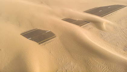 road over taken by sand dunes