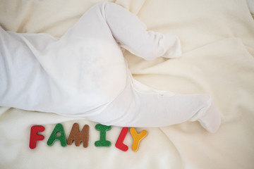 Obraz na płótnie Canvas family text wooden word top view on blanket with baby body and copy space background