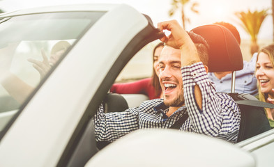 Happy friends with hands up having fun in convertible car on summer vacation