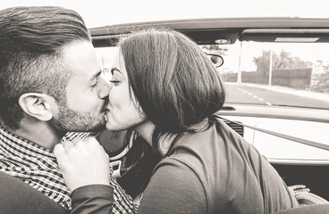Happy couple kissing inside convertible car
