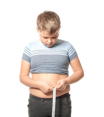 Overweight boy measuring his waist on white background