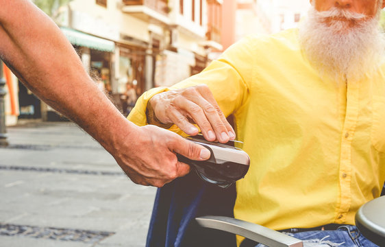 Male customer paying with contactless credit card with NFC technology - Waiter with a credit card reader machine at bar outdoor - New tech payment concept