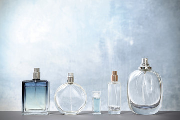 Different perfume bottles on table against color background