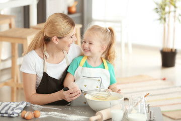 Mother and daughter making dough together in kitchen