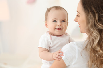 Young mother with her cute little baby on blurred background