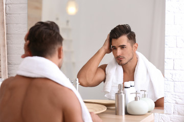 Young man with stubble ready for shaving near mirror in bathroom