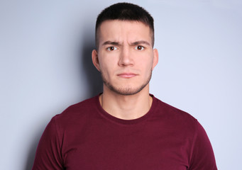 Emotional young man with dyed eyebrows on light background