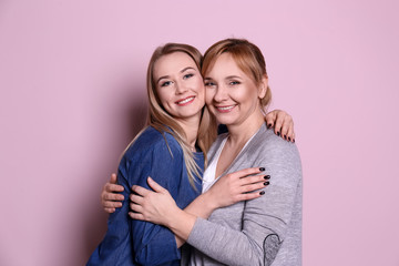 Young woman with her mother on color background