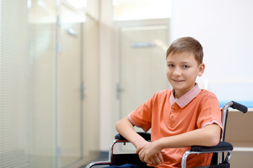 Little boy sitting in wheelchair indoors