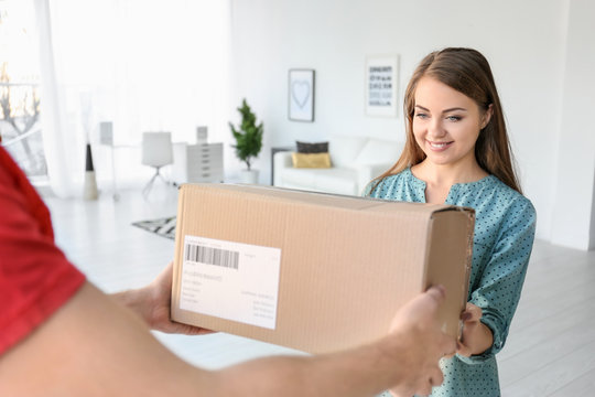 Young woman receiving parcel from courier