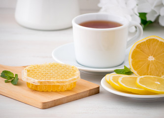 White Cup with tea, lemon slices and honey in honeycomb on white