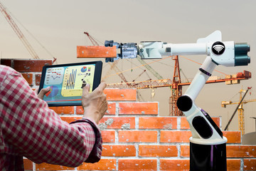 Man holding a tablet Remote control Smart robot industry 4.0 arm brick building construction human...