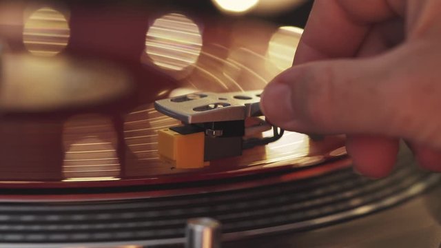 A slide turntable vinyl record player. The vinyl record on DJ turntable record player close up. The stylus smoothly with a needle onto a rotating red vinyl plate. Included gramophone and torque plate 