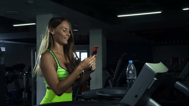 Girl takes a selfie in the gym, woman is photographed on the treadmill