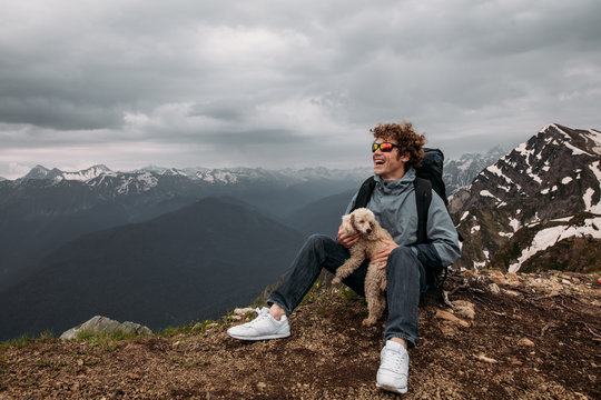 cheerful man is hiking with fdog in mountaines. full length photo