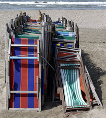 front view of old very colorful beach chairs closed and lined with inclined arrangement suitably tied by a top