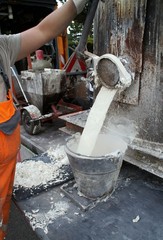 Ein Arbeiter füllt thermoplastisches Material für Strassenmarkierungen ab