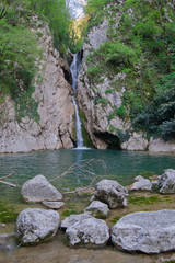 Naklejka na ściany i meble waterfall in the rocks among the green trees