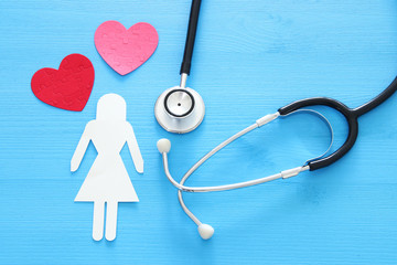 women healf Insurance . concept image of Stethoscope and female figure on wooden table. top view.