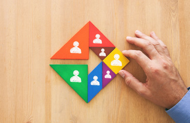 image of tangram puzzle blocks with people icons over wooden table ,human resources and management concept.