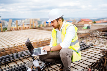 Construction engineer, architect planning with laptop, using technology at construction site