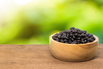Black bean in a bowl on wooden table with bokeh background