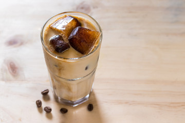 Espresso coffee frozen into ice cube mixed with milk on wooden background