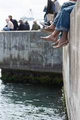 Couple of male feet at the harbor dock during summer. Relaxing summer scene