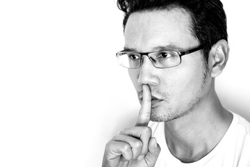 Shh! Handsome Asian man makes secret gesture with finger on his mouth.