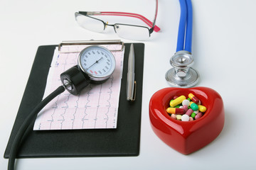 Red heart, asorted pils, glasses and a stethoscope on white background.