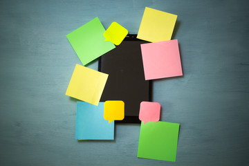 Colorful blank sticky notes covering an open screen tablet. Workload congestion. 
