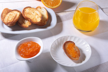 Morning Breakfast set with orange jam on bread toast and juice in glass.