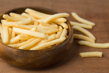 French fries or potato fry in wooden bowl putting on linen and wooden background.