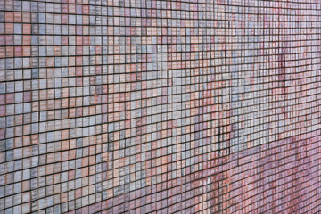 The texture of an uneven old wall covered with tiles