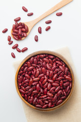 Red beans in wooden bowl and spoon putting on linen and white background.